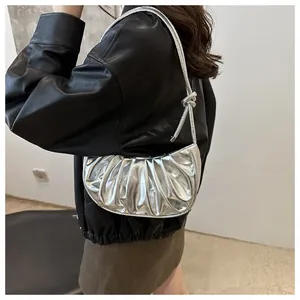 Close-up of metallic silver pleated crescent bag with knot detail and shiny Y2K finish