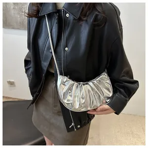 Detail of silver metallic pleated crescent bag with high-gloss finish and smooth texture