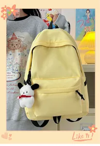 Close-up of light yellow nylon backpack with front pocket and plush puppy keychain