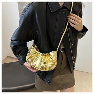 Detail of metallic gold pleated dumpling bag with glossy finish and fine chain strap