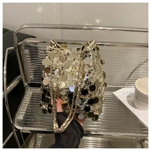Dettaglio di paillettes oro e argento su una borsa a secchiello alla moda con catena