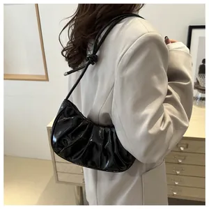 Detail of black glossy pleated dumpling bag with cylindrical knotted shoulder strap