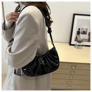 Detail of black glossy pleated hobo bag showing vertical folds and silver buckle