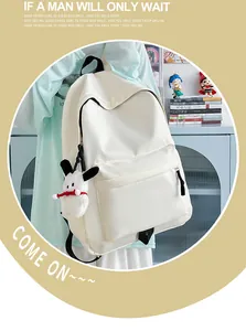Detail view of a white nylon backpack with a plush dog charm and black zipper ribbon straps