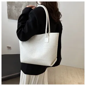 Detailed view of the woven texture on a white minimalist tote bag carried by a model