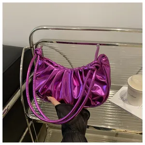 Close-up of metallic purple pleated dumpling bag with knot detail on glass shelf