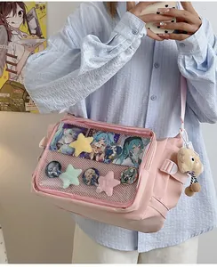 Detail of pink ita bag with clear PVC window showing anime badges and plush star charms