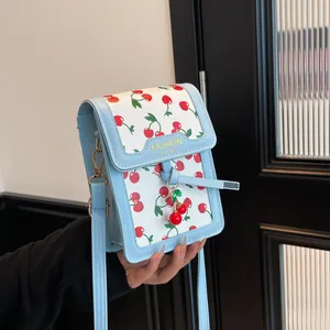 Mini crossbody bag with cherry print and blue leather strap in a retro French style