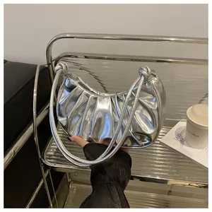 Detailed close-up of glossy silver pleated crescent bag with knotted handle detail
