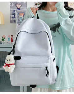 Detail view of a solid color nylon backpack with a plush charm and front zipper pocket