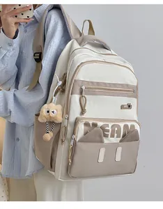 Detail of beige and khaki school backpack with plush owl charm and DREAM lettering