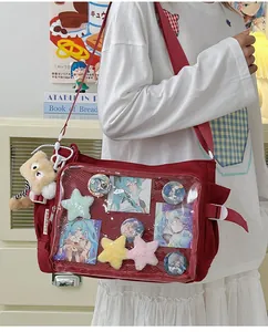 Detailed view of a red canvas ita bag with clear window and plush bear charms