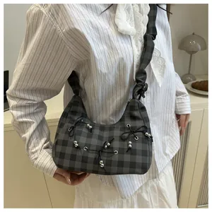 Detail der karierten Falten-Schultertasche mit Schleifen und silbernen Perlen