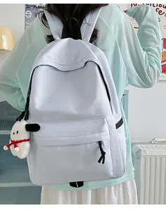 Detail view of light blue nylon backpack with cute plush charm and water-resistant surface