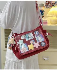 Detail of red canvas ita bag featuring a clear PVC window filled with anime pins and stars