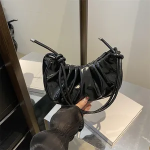 Glossy black pleated half-moon hobo bag with knotted strap and metallic accents