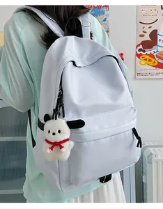 Detail of minimalist nylon backpack showing side pocket with plush pendant and zipper closure