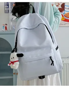 Detail of light blue nylon backpack with white plush puppy pendant for students