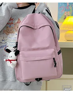 Detail of a minimalist pink nylon backpack with a large front pocket and a plush pendant