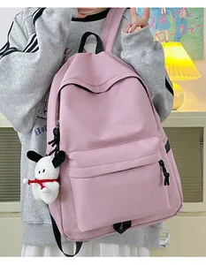 Detailed view of pink nylon school backpack with a cute white puppy plush pendant attached