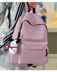 Detailed view of pink nylon backpack featuring a white puppy plush charm and multiple pockets