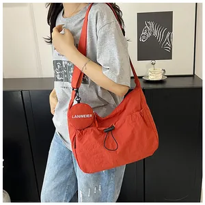 Détail du sac à bandoulière en toile orange avec cordon et petit porte-monnaie rond