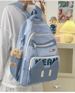 Detailed close-up of a blue canvas backpack with cat ear design and plush bear charm