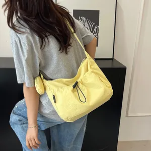 Détail du sac croissant en nylon jaune avec cordon et pochette amovible porté par un modèle