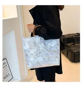 Detailed view of white jacquard fabric pattern and natural bamboo handle on a tote bag