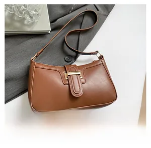 Flat lay of a brown crescent shoulder bag with golden buckle on a grey suit jacket
