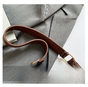 Detail of brown litchi pattern leather bag showing wide strap and gold metal hardware