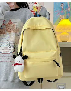 Detail of a bright yellow nylon backpack with a cute white puppy plush charm and adjustable straps