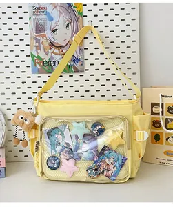 Detail of light yellow ita bag with large transparent PVC pocket and plush charm accessory