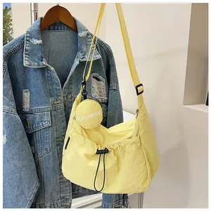 Détail du sac bandoulière en nylon jaune clair avec petite pochette ronde assortie