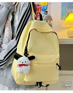 Detail of light yellow nylon backpack with a plush character charm on front pocket