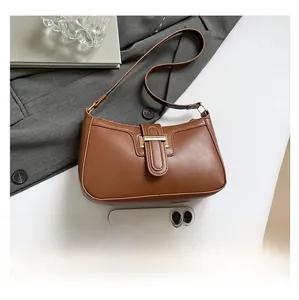Brown leather crescent shoulder bag shown with a smartphone for size comparison