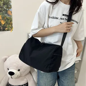 Vue détaillée du grand sac bandoulière en nylon noir avec large sangle réglable