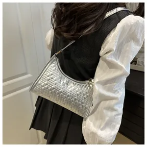 Silver quilted half-moon shoulder bag with metallic finish shown on model's shoulder