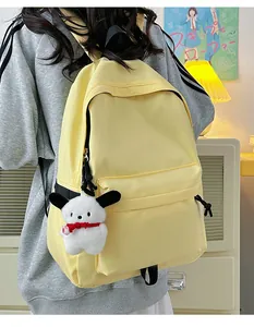 Detail of light yellow nylon backpack with a white plush dog charm on the front pocket