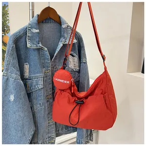 Détail du sac hobo en nylon orange avec cordon de serrage et petit porte-monnaie rond