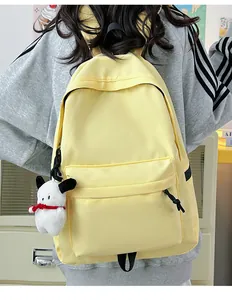 Detail view of a bright yellow nylon backpack featuring a cute white puppy plush charm