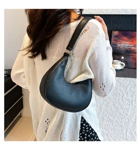 Litchi pattern leather crescent shoulder bag shown on model with gold hardware details