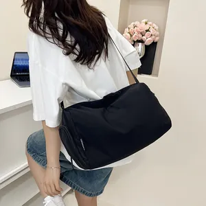 Détail du sac de sport en nylon noir brillant avec poche zippée et étiquette latérale