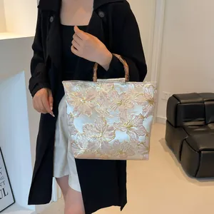 Elegant jacquard tote bag with floral patterns and natural bamboo handles shown with model