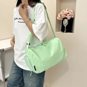 Détail du sac cylindre en nylon vert menthe avec poche zippée latérale et étiquette tissée