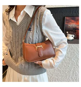 Brown vintage PU leather crescent shoulder bag with golden metallic buckle worn by model
