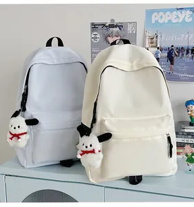 Detail of light blue and beige nylon backpacks with cute plush pendants in a trendy setting