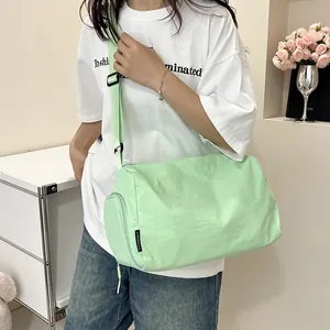 Détail du sac cylindrique en nylon vert menthe montrant la texture plissée et l'étiquette