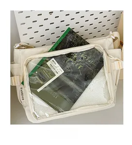 Detail of off-white canvas crossbody bag featuring a transparent front window pocket