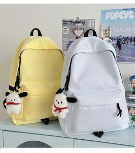 Detail of light blue and yellow nylon backpacks with plush puppy pendants in a room